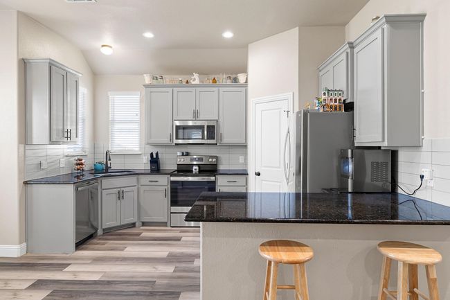 Kitchen featuring tasteful backsplash, stainless steel appliances, light wood-style floors, a sink, and a peninsula | Image 11