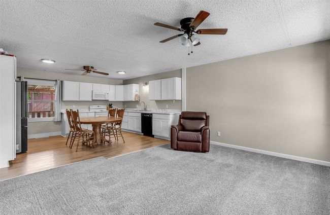 Dining area with ceiling fan, light carpet, a textured ceiling, and baseboards | Image 6