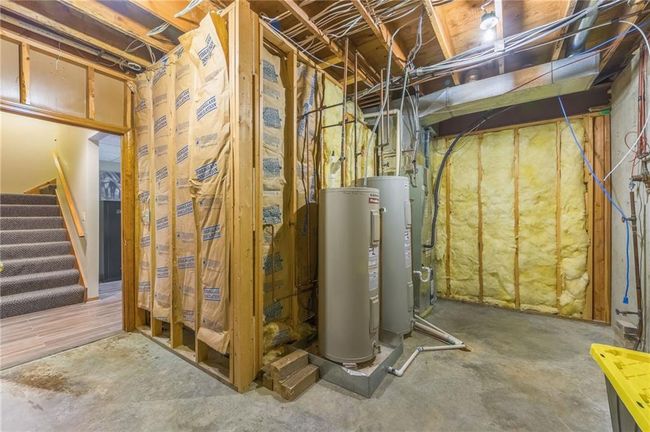 Unfinished basement featuring stairway and electric water heater | Image 65