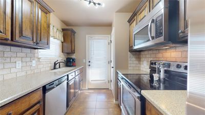 Kitchen with light stone counters, plenty of natural light, sink, appliances with stainless steel finishes, and light tile patterned floors | Image 3