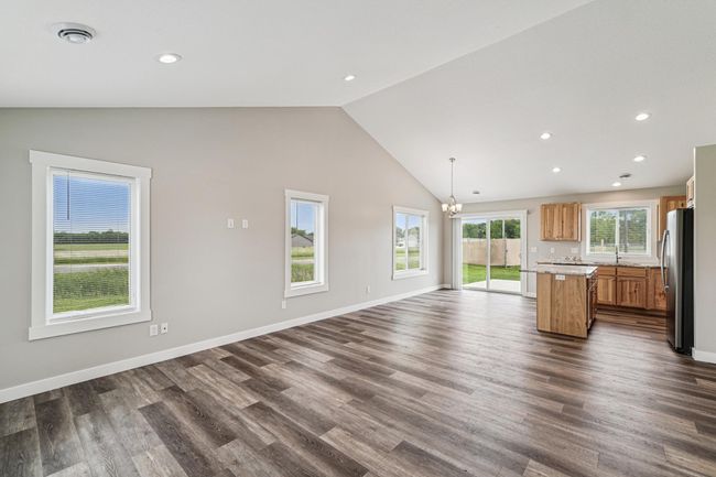 The living room features LVP flooring, vaulted ceilings, and recessed lights. | Image 8