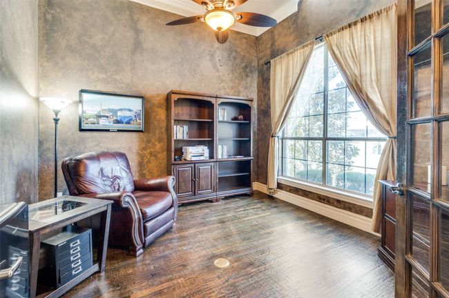 Living area featuring dark wood-type flooring, plenty of natural light, a ceiling fan, and baseboards | Image 4