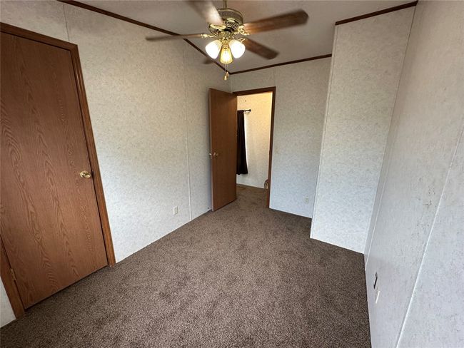 Unfurnished room featuring carpet floors, ceiling fan, a textured wall, and crown molding | Image 28