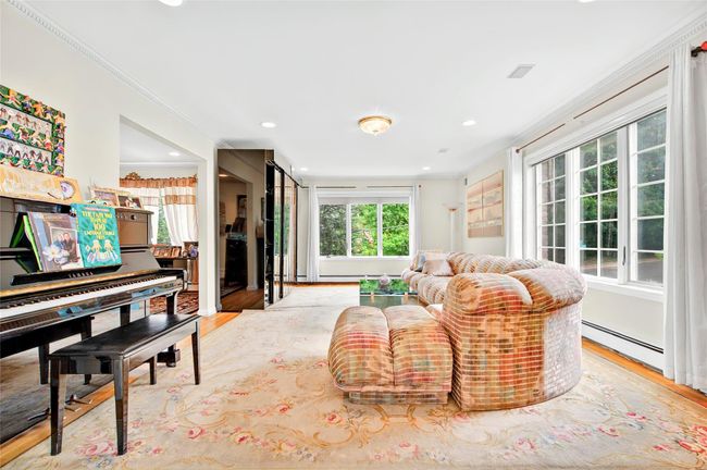Living area featuring baseboard heating, crown molding, light wood-style floors, and recessed lighting | Image 6