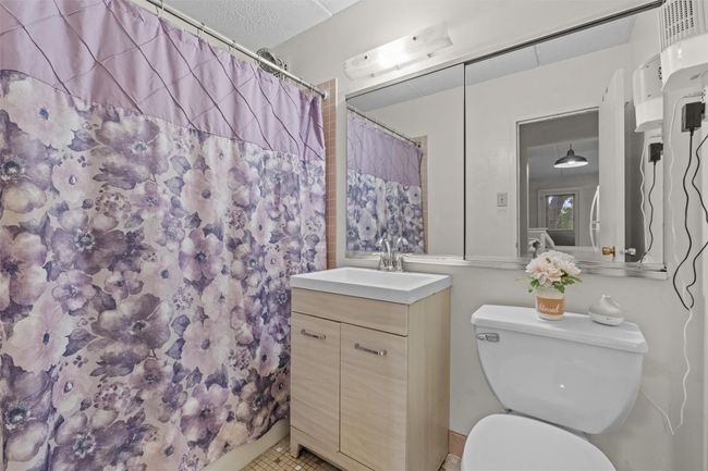 Full bathroom with vanity, toilet, a shower with shower curtain, and tile patterned flooring | Image 10