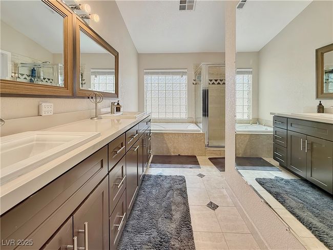 Full bath featuring tile patterned flooring, visible vents, a shower stall, double vanity, and a bath | Image 27