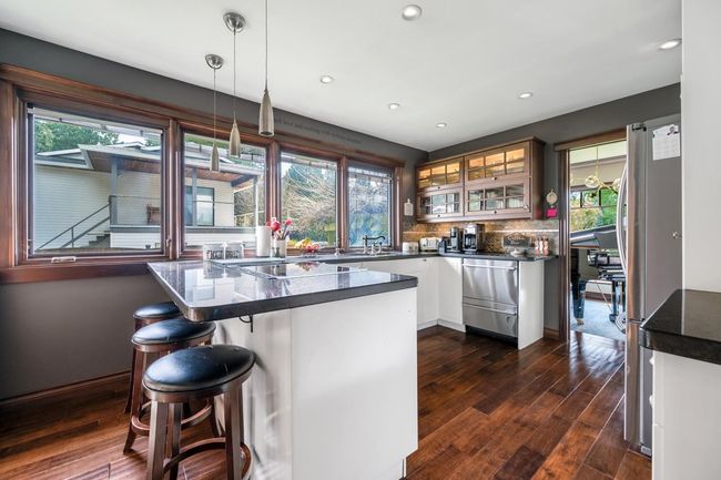 Kitchen featuring dark countertops, plenty of natural light, glass insert cabinets, and freestanding refrigerator | Image 7