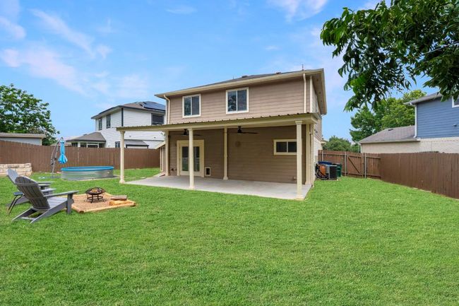Rear view of property with a fenced backyard, a ceiling fan, an outdoor fire pit, and a patio | Image 32