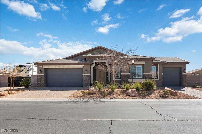 View of front of house with a garage, stone siding, decorative driveway, and stucco siding | Image 54
