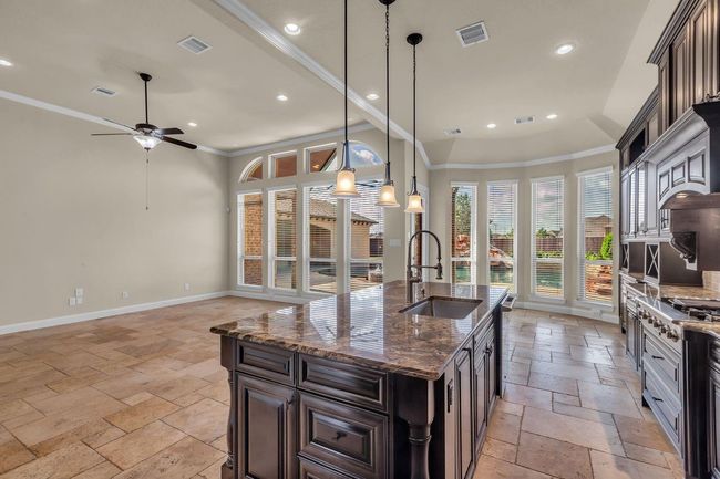 Natural light fills the space through large windows, while the kitchen’s design complements the comfortable living room setup. | Image 11
