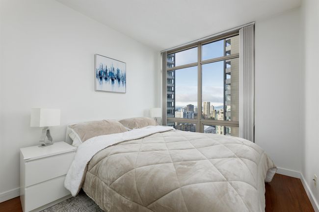 Bedroom with a city view, baseboards, wood finished floors, and a wall of windows | Image 11