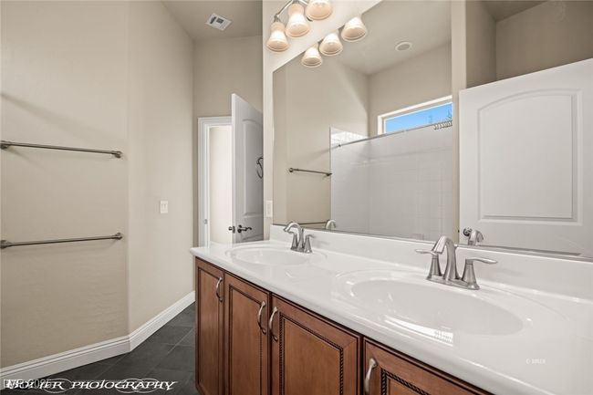 Full bathroom with a sink, baseboards, double vanity, and tile patterned flooring | Image 36