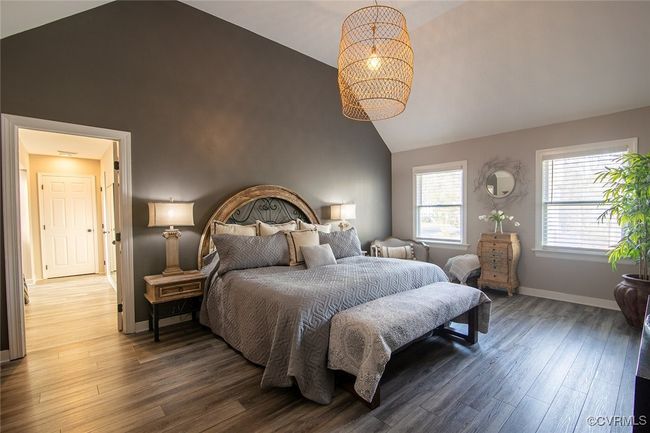 Bedroom featuring baseboards, high vaulted ceiling, an inviting chandelier, and wood finished floors | Image 33