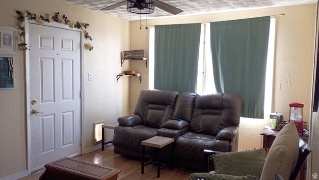 Living area with a ceiling fan, wood finished floors, and a textured wall | Image 22