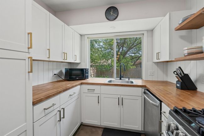 Kitchen featuring butcher block countertops, open shelves, a sink, and appliances with stainless steel finishes | Image 11