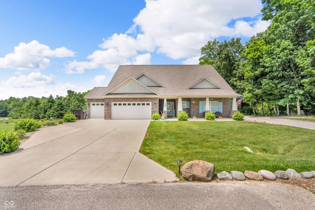 craftsman-style house featuring concrete driveway, an attached 3 car garage, covered porch, and brick siding | Image 44
