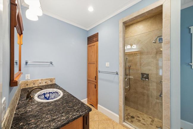 PRIMARY BATH OFFERS A GRANITE VANITY AREA SURROUNDING THE CUSTOM SINK. SEAMLESS SHOWER OFFERS CUSTOM CERAMIC TILE | Image 27