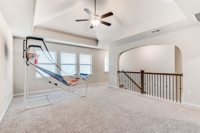 Rec room featuring a raised ceiling, carpet floors, ceiling fan, and baseboards | Image 15
