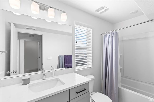 Full bath featuring shower / bath combination with curtain, visible vents, vanity, and toilet | Image 20