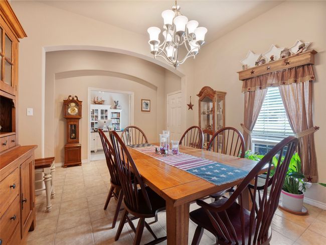 Dining space with a chandelier, arched walkways, light tile patterned flooring, and baseboards | Image 4