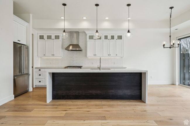 Kitchen featuring decorative backsplash, appliances with stainless steel finishes, wall chimney range hood, and a sink | Image 8