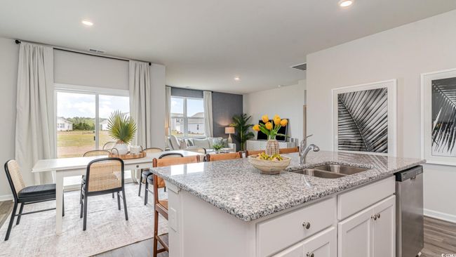 Kitchen featuring a sink, dishwasher, wood finished floors, an island with sink, and white cabinets | Image 13