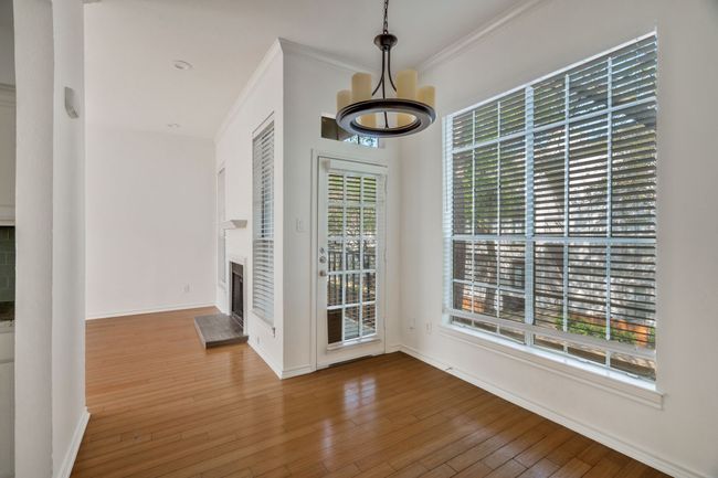 Unfurnished dining area featuring wood-type flooring, baseboards, crown molding, and a fireplace | Image 9