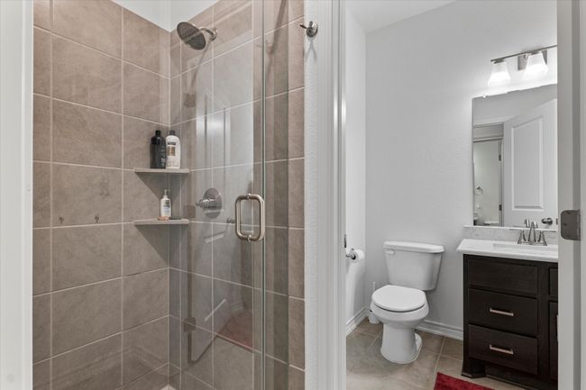 Bathroom with a shower stall, toilet, tile patterned flooring, and vanity | Image 29