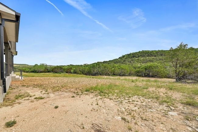 A large cleared backyard sits behind the home, stretching to the wooded acreage beyond the yard line. | Image 38