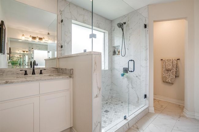 Full bath featuring a stall shower, vanity, and marble look tiles | Image 5