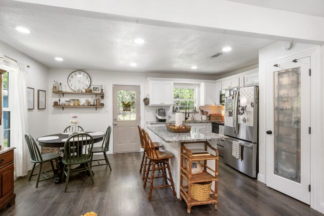 Kitchen featuring freestanding refrigerator, dark wood finished floors, a breakfast bar, white cabinets, and a kitchen island | Image 5
