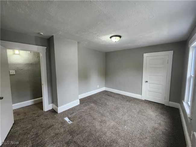 Unfurnished room with a textured ceiling, a healthy amount of sunlight, and dark carpet | Image 17