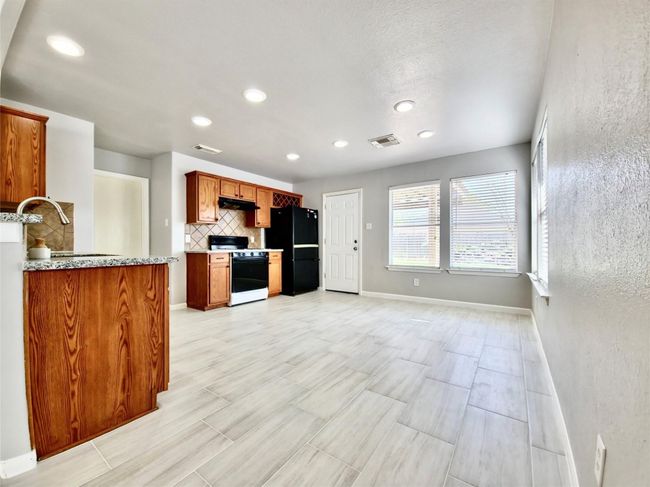 Kitchen with stove, freestanding refrigerator, tasteful backsplash, recessed lighting, and under cabinet range hood | Image 9
