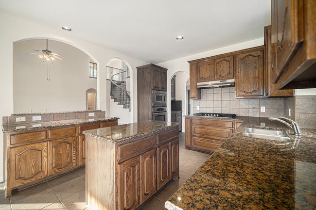 Kitchen featuring arched walkways, a sink, appliances with stainless steel finishes, ceiling fan, and a kitchen island | Image 10