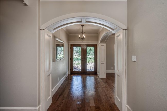 Step through elegant wooden doors with iron accents into a stunning entryway highlighted by beautifully framed arches. | Image 6