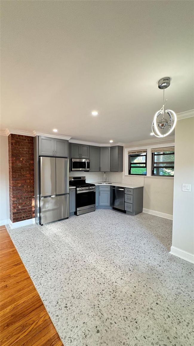 Kitchen featuring ornamental molding, gray cabinets, stainless steel appliances, light countertops, and pendant lighting | Image 6