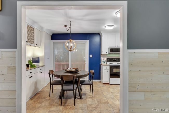 Updated eat in kitchen with custom built-in pantry & bar area, new chandelier, newer sliding patio doors with built-in blinds that lead to back deck, quartzite countertops. | Image 10