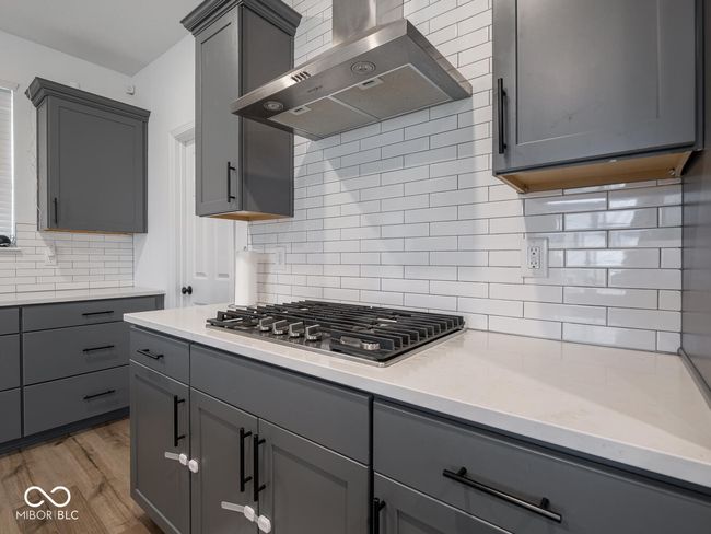kitchen featuring gray cabinets, wall chimney range hood, and stainless steel gas stovetop | Image 21