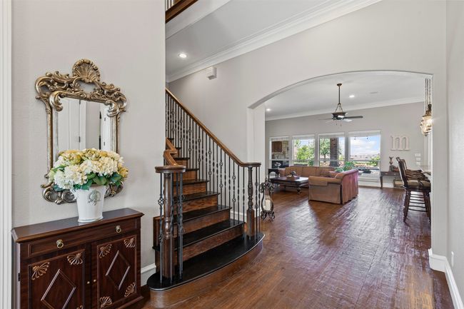 Stairs featuring arched walkways, a ceiling fan, ornamental molding, and wood finished floors | Image 13