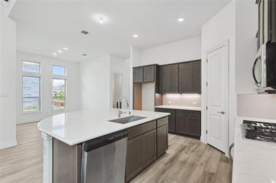 Kitchen with backsplash, light hardwood / wood-style floors, sink, a center island with sink, and stainless steel appliances | Image 3