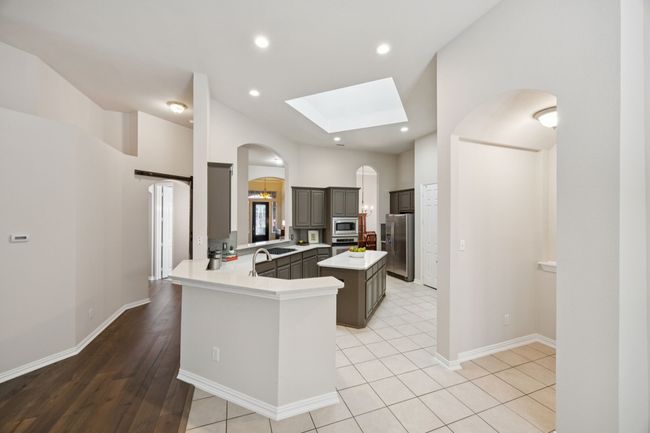 A wide and efficient layout includes a central island, walk-in pantry, built-in stainless appliances, and a large breakfast bar that perfect for entertaining or meals on the go. | Image 8