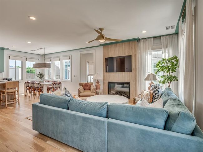 Living room with recessed lighting, a large fireplace, a ceiling fan, light wood finished floors, and baseboards | Image 8