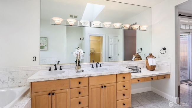 The wooden cabinet adds warm contrast to this modern en suite bathroom, which offers ample storage, a spacious countertop with two sinks, and a large mirror above | Image 13