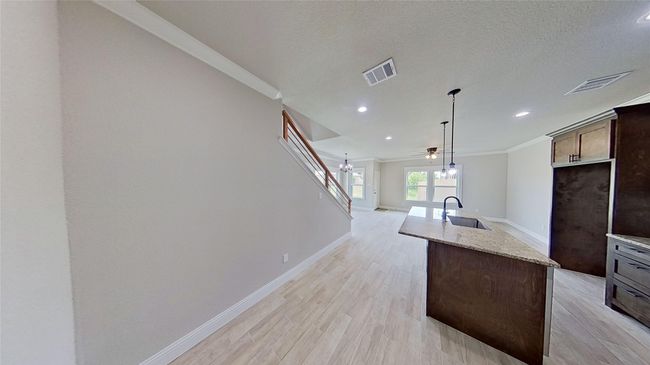 Kitchen with light wood-style flooring, a center island with sink, visible vents, and a sink | Image 15