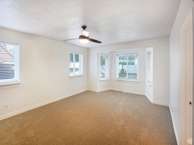 Unfurnished room with light carpet, a textured ceiling, visible vents, baseboards, and ceiling fan | Image 14