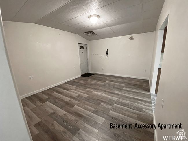 Empty room with a paneled ceiling, visible vents, baseboards, and wood finished floors | Image 19