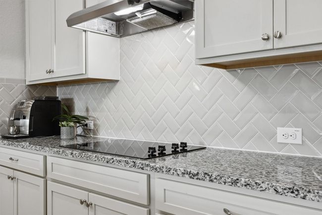 Kitchen featuring gorgeous tile backsplash, granite counters, vent hood over electric cooktop and spacious cabinets | Image 7
