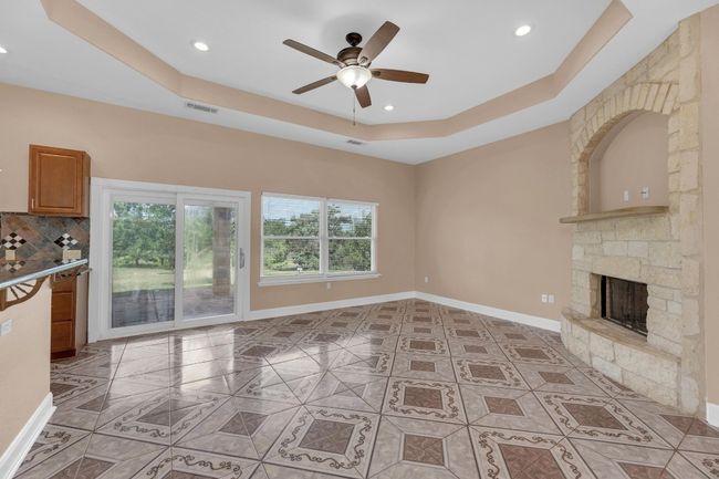 Unfurnished living room featuring a tray ceiling, healthy amount of natural light, recessed lighting, and ceiling fan | Image 15