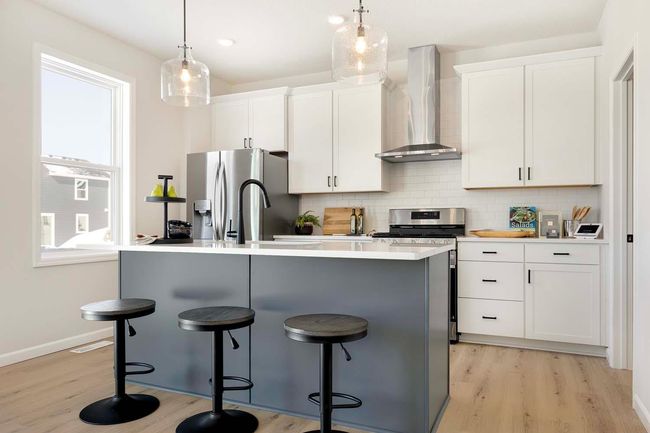 Kitchen includes quartz countertops, ceramic tile backsplash, gas stove and stainless steel hood vented to exterior. | Image 5