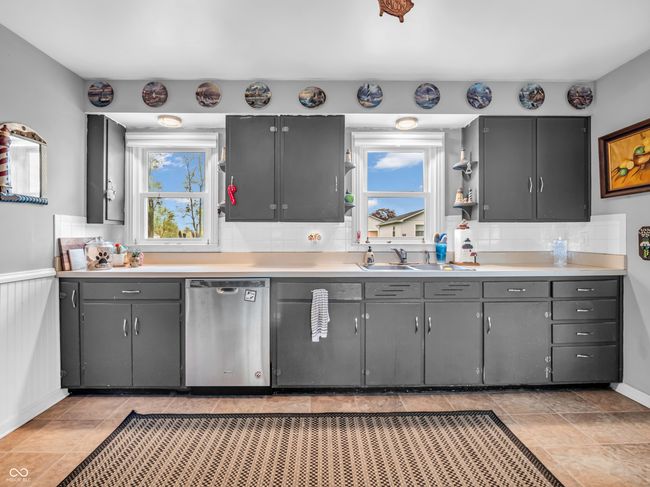 kitchen with gray cabinets, tasteful backsplash, light countertops, dishwasher, and a sink | Image 17